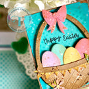 Easter card with colorful eggs and a pink bow on a blue background, featuring Trinity Stamps logo.