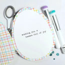 Card with text 'wishing you a basket full of joy' on a white background with stationery items.