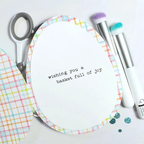 Card with text 'wishing you a basket full of joy' on a white background with stationery items.