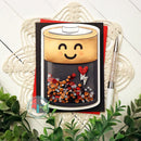 Card with a smiley face battery design on a white surface with plants and a pen.