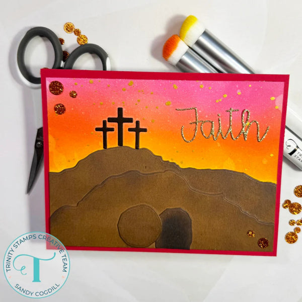 Card with three crosses and the word 'Faith' on a sunset background, surrounded by crafting tools.