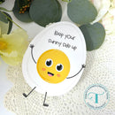 Circular card with a smiling sun illustration and text 'Keep your sunny side up' on a textured surface with flowers.