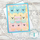Card with pastel-colored bunny faces and 'Happy Easter' text on a textured surface.