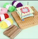 Wooden pegboard with crocheted blanket and colorful yarn balls on a light green background