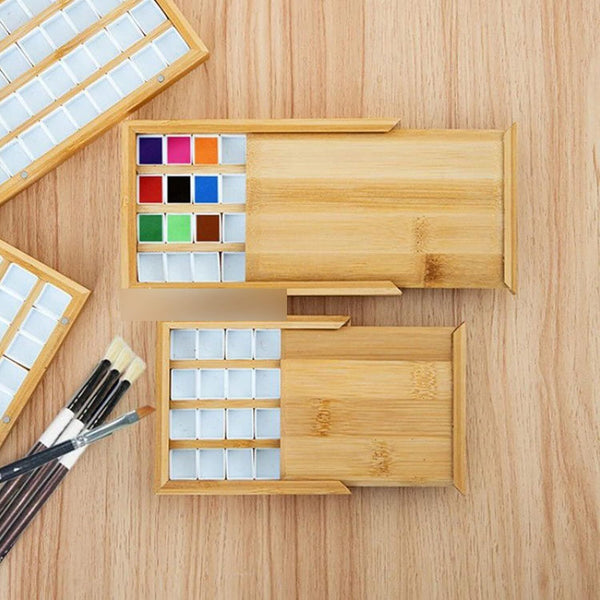 Wooden art supply set with watercolor paints and brushes on a wooden surface
