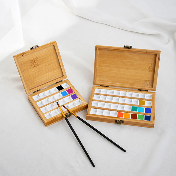 Wooden art palette with watercolor paints and brushes on a white background