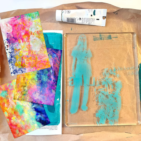 Art supplies including colorful abstract paintings and a stenciled design on brown paper.
