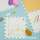 Grid-patterned foam mats with yarn and tools on a light blue background