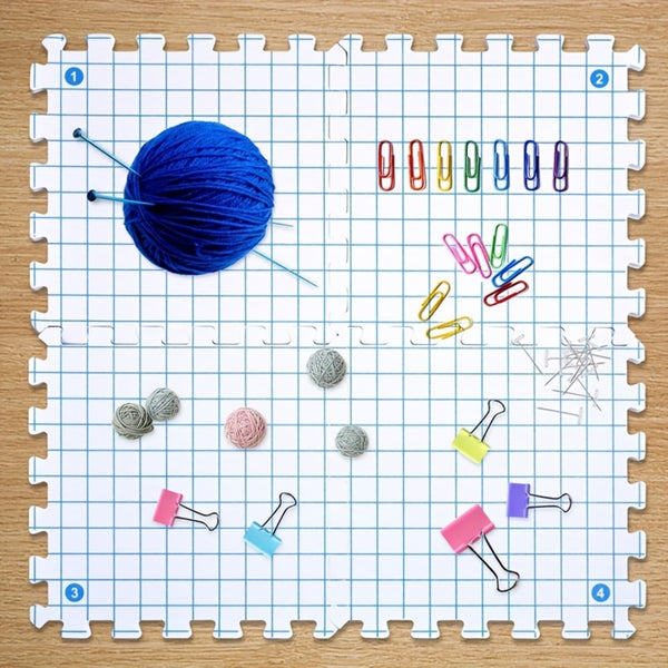 Grid-patterned mat with yarn ball, paper clips, and small items on a wooden surface