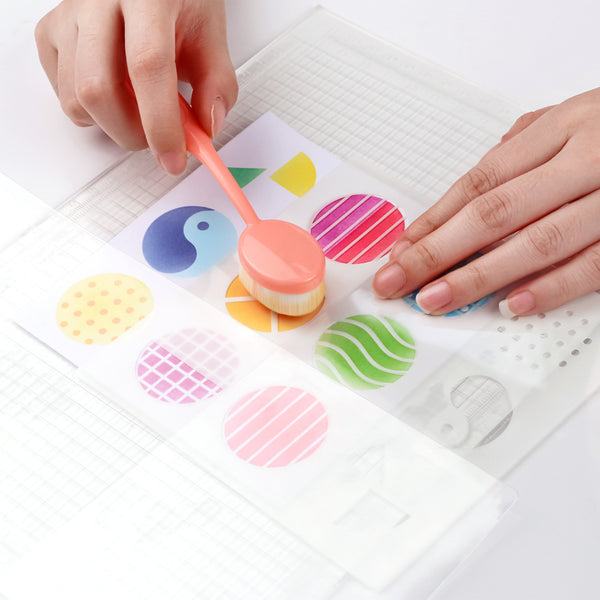 Colorful stamp with a hand holding it over a sheet of paper with printed designs.