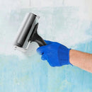 Hand wearing a blue glove using a metal roller on a textured surface