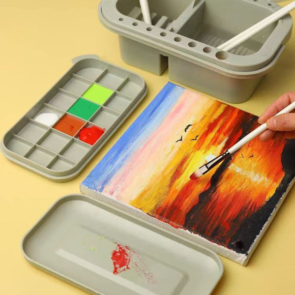 Artistic setup with watercolor paint set, color swatches, and a painted scene on a yellow background.