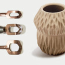 Beige textured vase with three bronze bottle openers on a light background