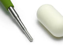 Green-handled tool with a metallic shaft and white ceramic component on a white background