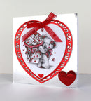 Greeting card with a heart-shaped design featuring a teddy bear and red ribbon on a white background.