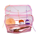 Pink mesh storage bag with yarn and knitting needles on a white background