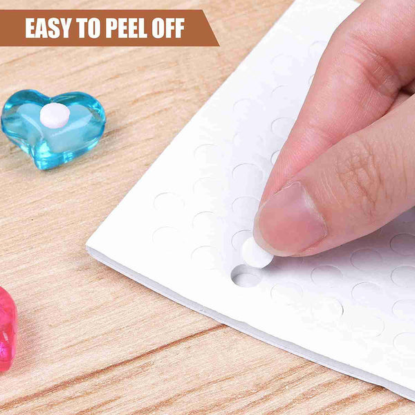 Hand peeling a small adhesive patch from a sheet on a wooden surface.