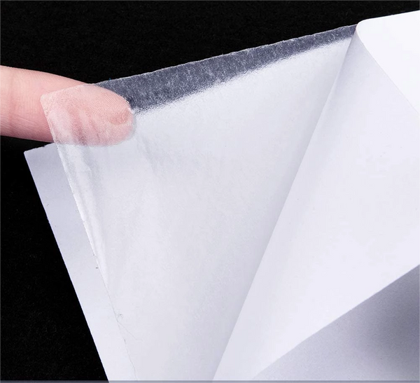 Clear plastic sheet held by a finger against a black background