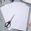 White paper sheets with a pair of scissors on a gray surface