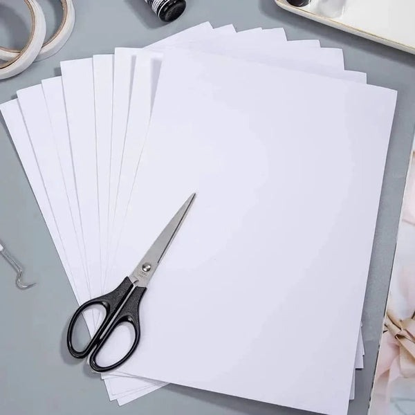 White paper sheets with a pair of scissors on a gray surface