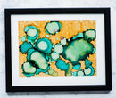 Framed abstract artwork with green and blue patterns on a yellow background
